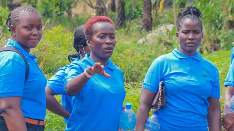 Trainees in blue shirts listening during a field session